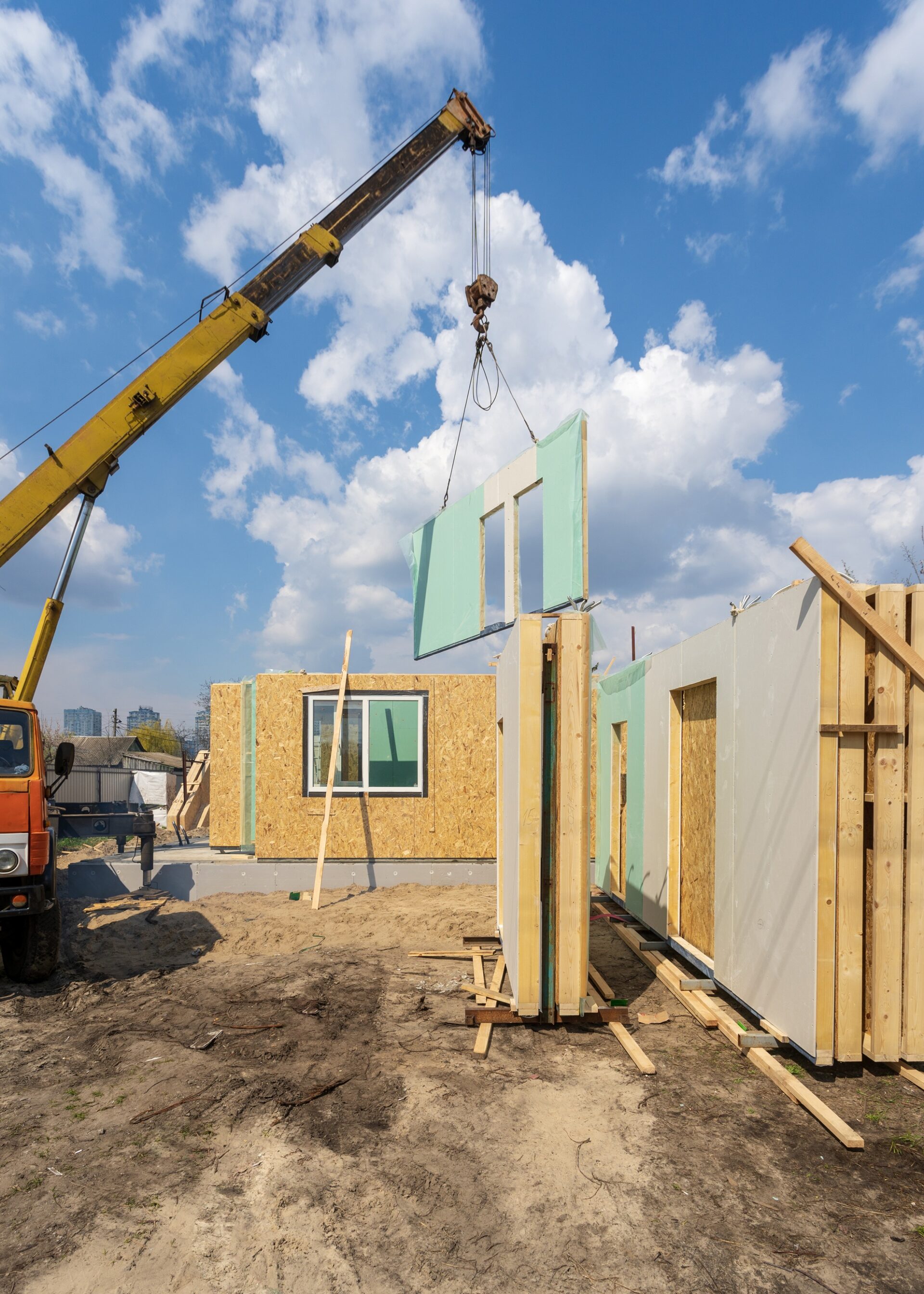Process of construction new and modern modular house from composite sip panels. Vertical photo of crane with wall against blue background sky